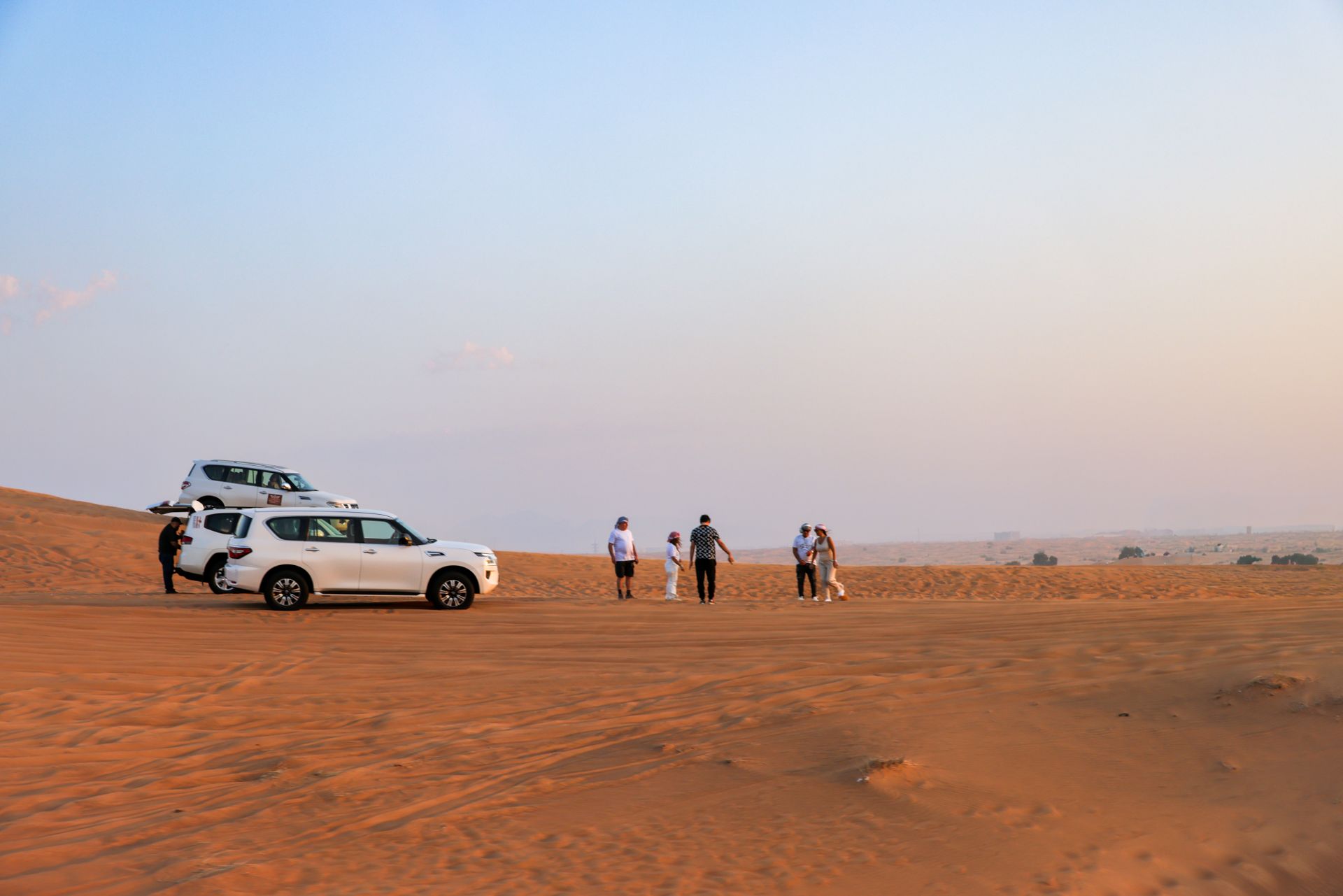 Tourists explore the desert landscape with off-road vehicles under a warm sky.