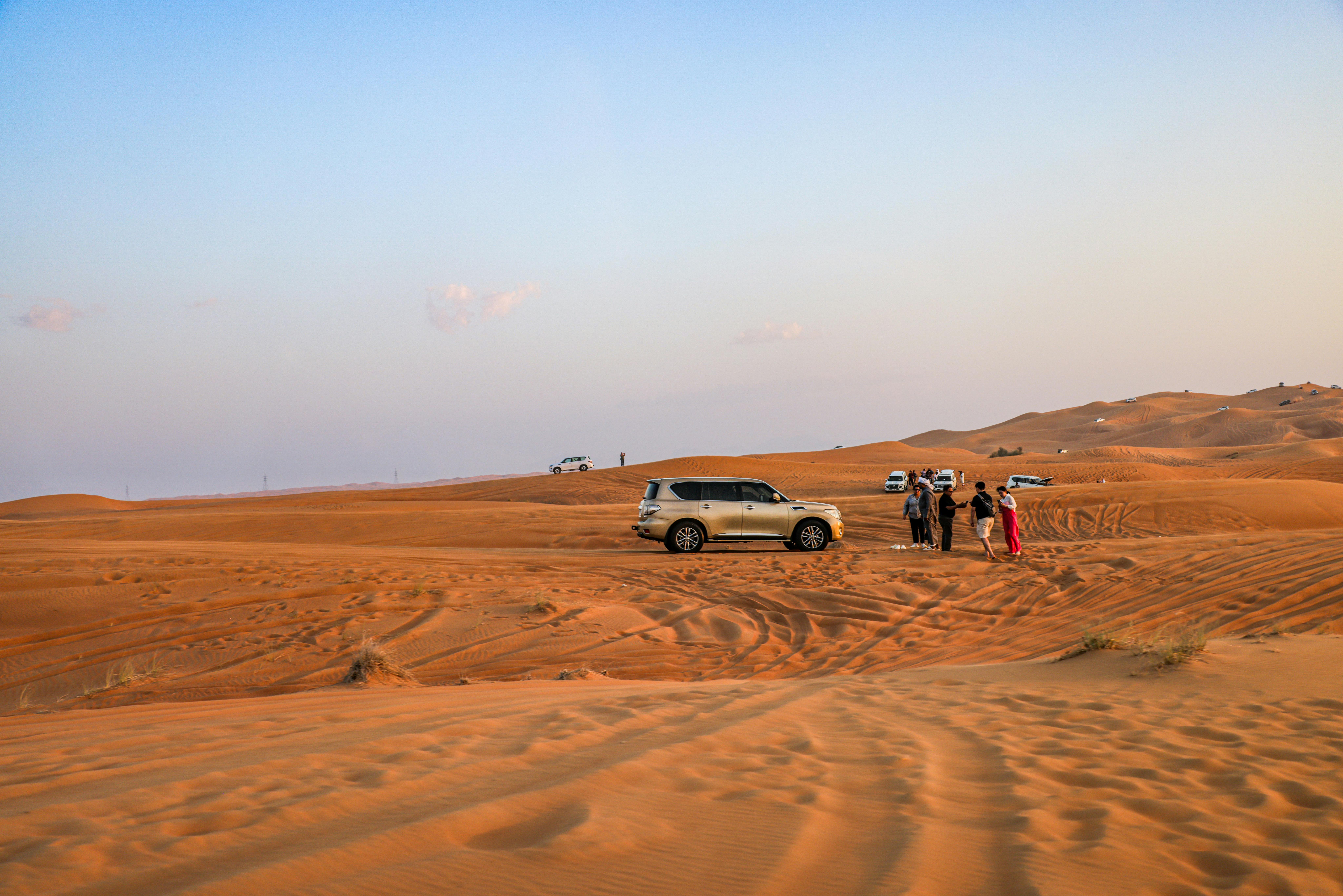 Explore an exhilarating desert safari with SUVs driving over sand dunes at sunset.