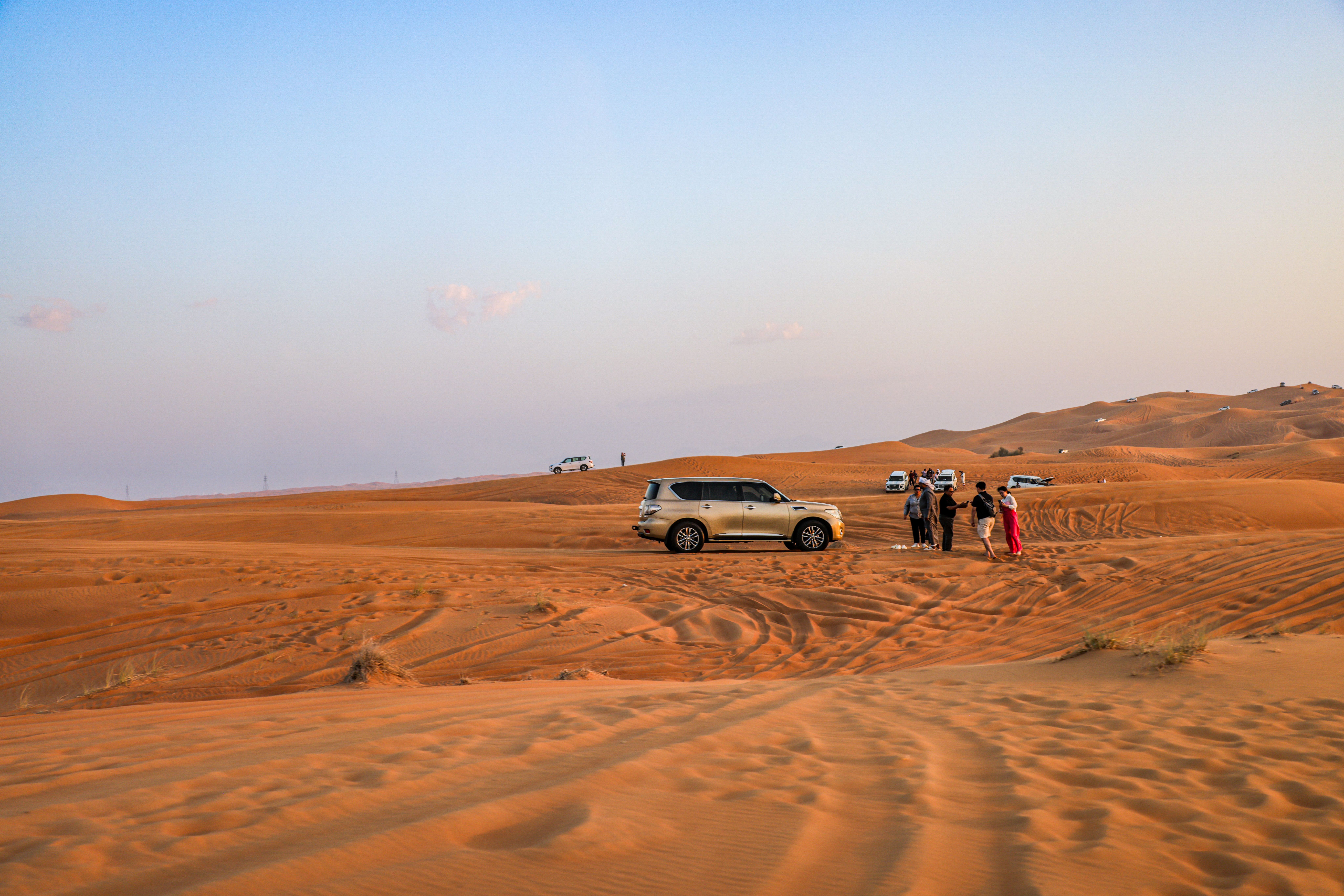 VIP desert safari in Dubai with SUVs on dunes at sunset