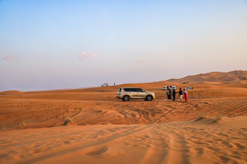 Free Explore an exhilarating desert safari with SUVs driving over sand dunes at sunset. Stock Photo