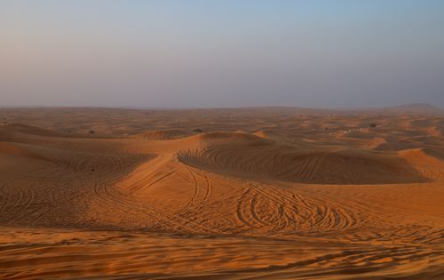 Free A breathtaking view of sand dunes under a sunset sky, capturing the essence of desert tranquility. Stock Photo