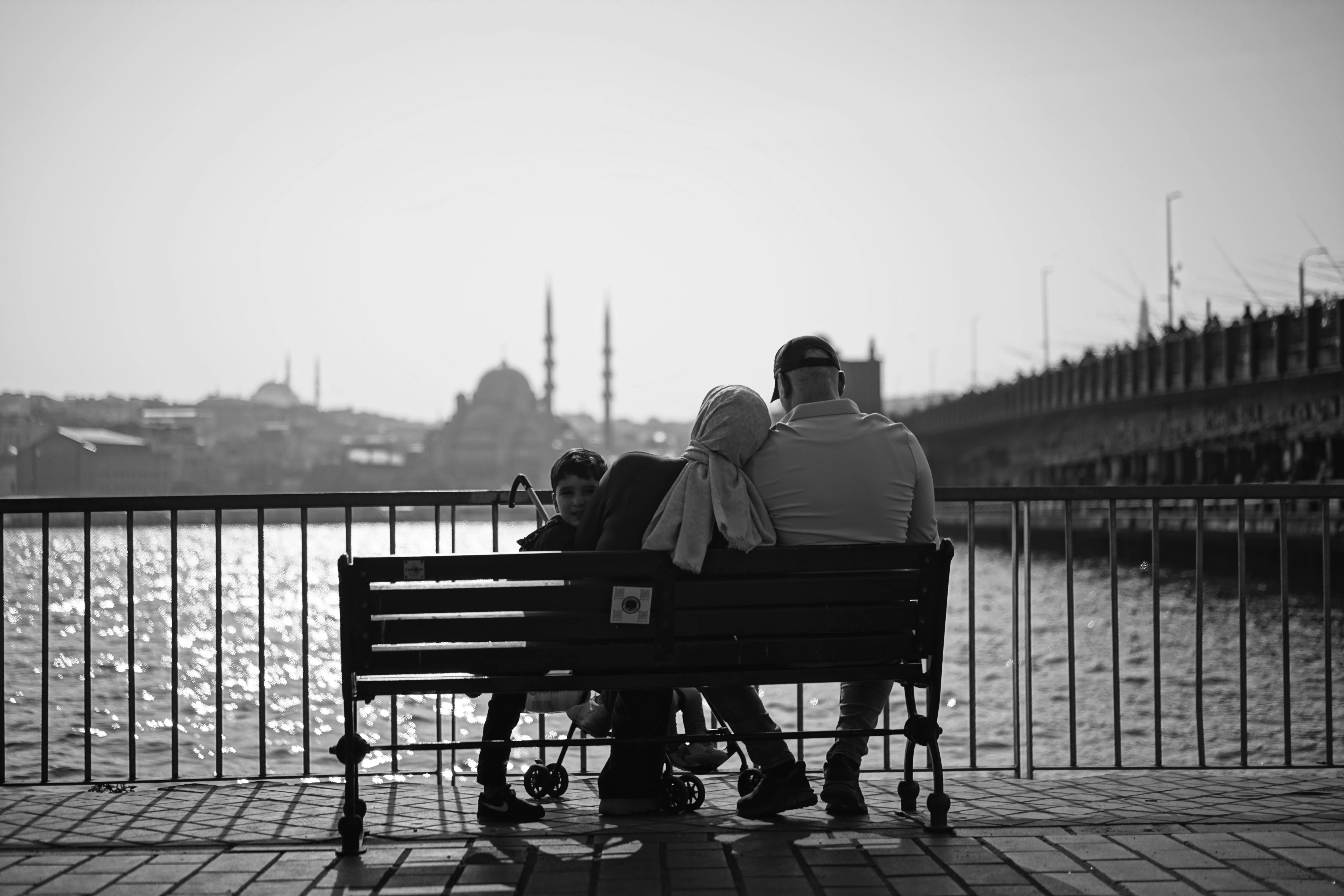 A family enjoys a peaceful moment on a bench overlooking the Istanbul skyline and waterfront.