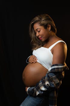 Side portrait of a pregnant woman lovingly holding her belly, embracing motherhood.