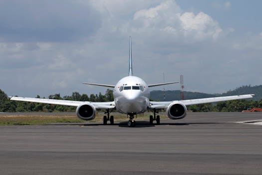 Front view of a commercial airplane positioned on a runway, preparing for takeoff under a cloudy sky.
