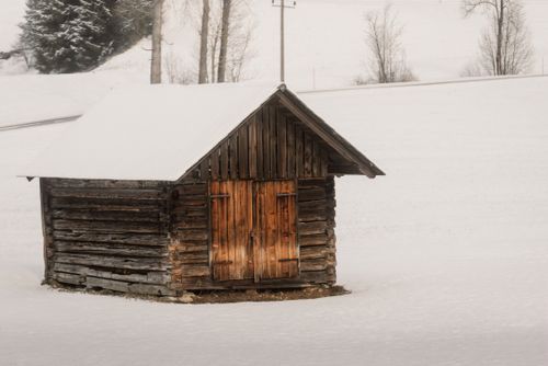 Free A solitary wooden cabin stands amidst a serene, snowy field, embodying rustic charm and winter solitude. Stock Photo