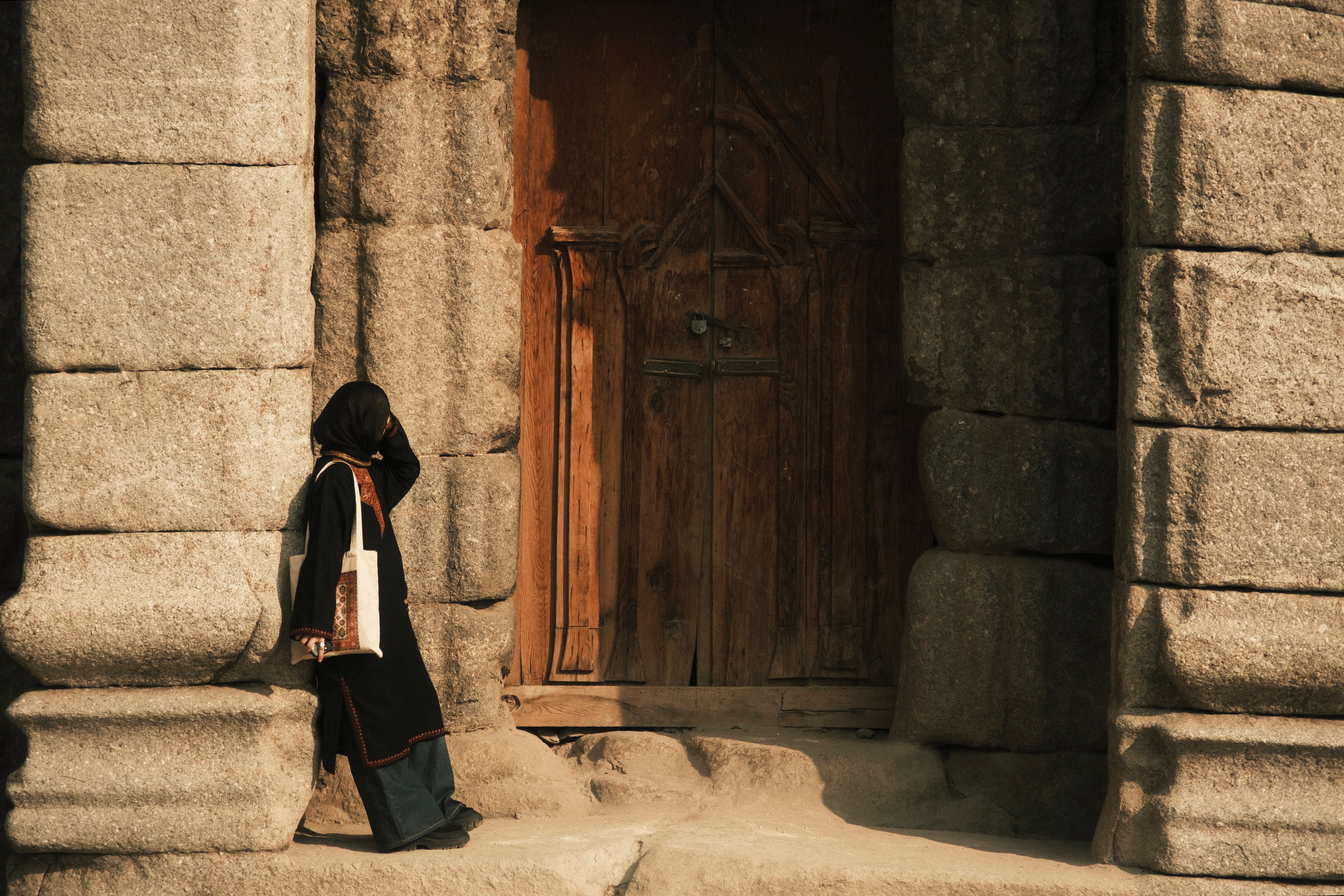 Woman in Traditional Dress Near Historic Doorway · Free Stock Photo