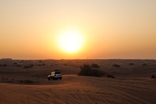 Free Stunning desert sunset with an SUV driving through sand dunes, capturing adventure and serenity. Stock Photo