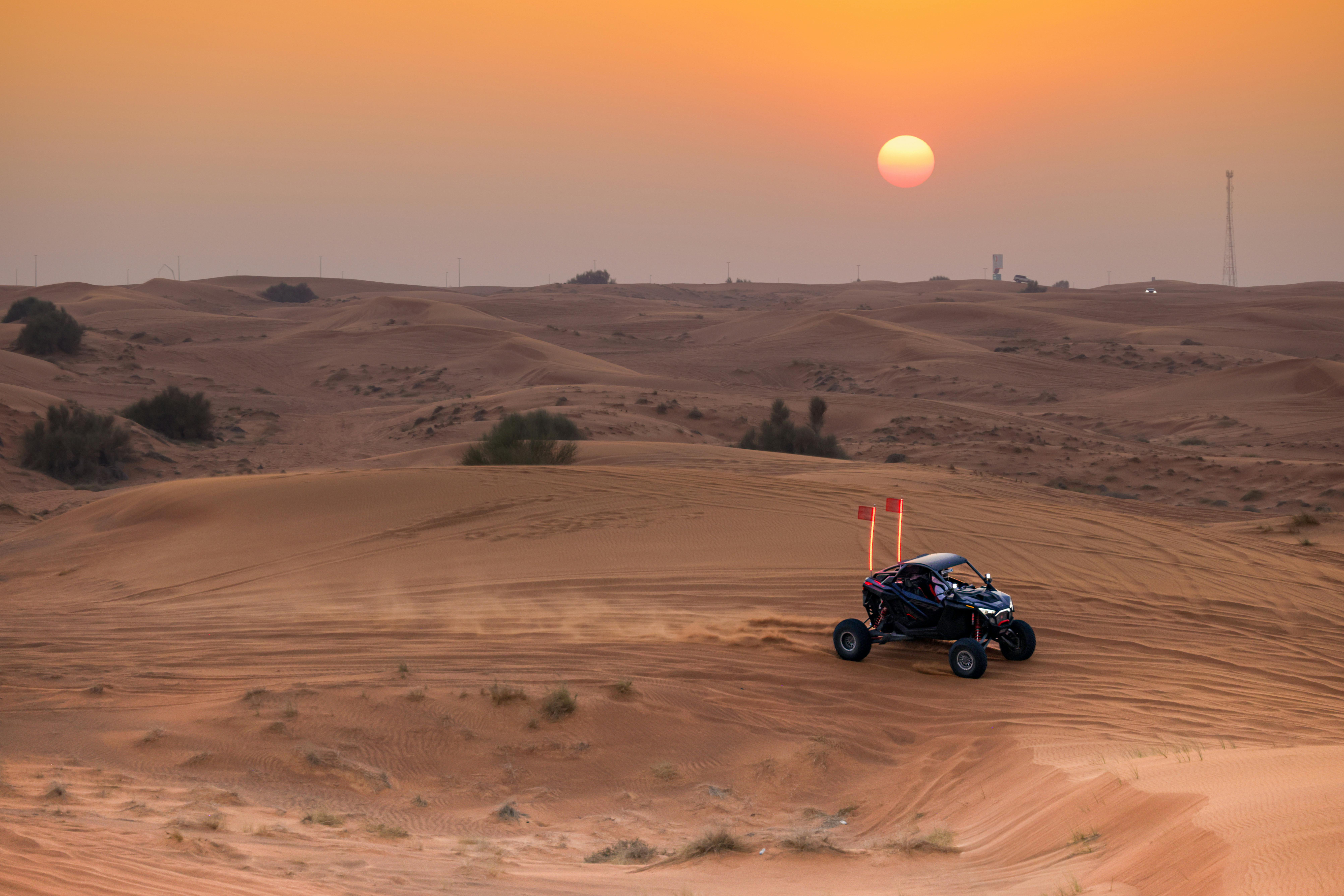 Dune buggy ride across desert dunes at sunset, highlighting adventure and nature.