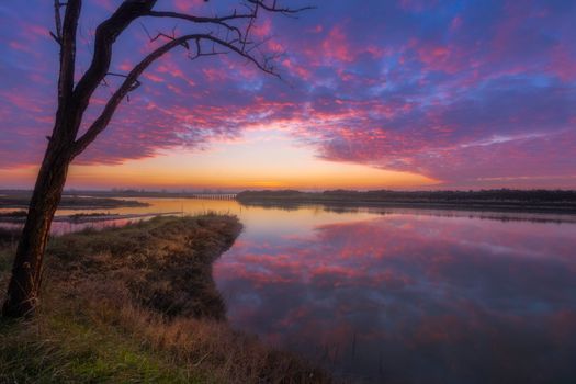 A stunning sunset over water with colorful sky reflection in Jesolo, Italy.
