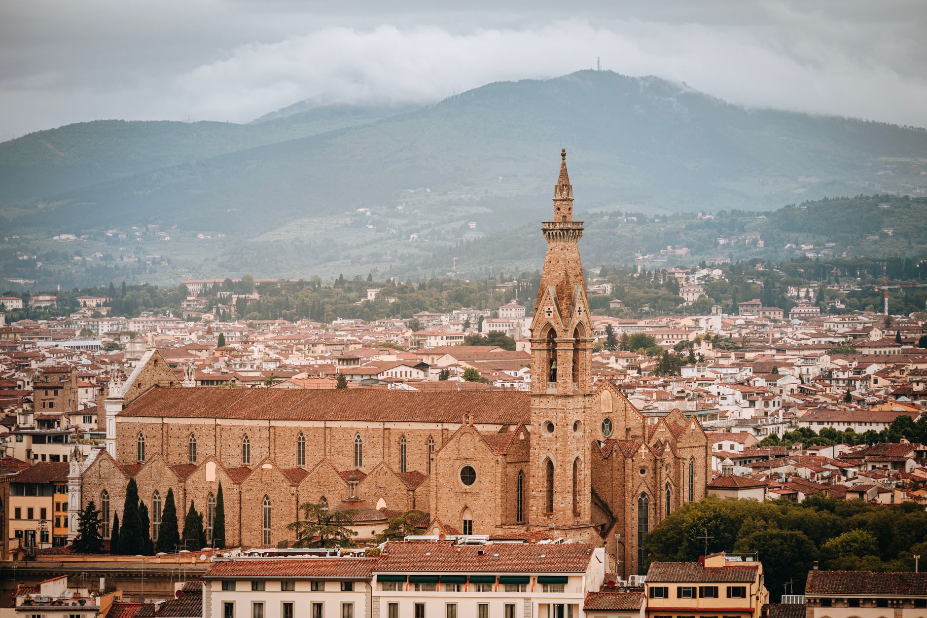 Aerial view of Santa Croce Basilica in Florence, showcasing gothic architecture and vibrant red rooftops.