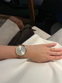 Close-up of a minimalist silver wristwatch on a woman's wrist, showcasing modern elegance.