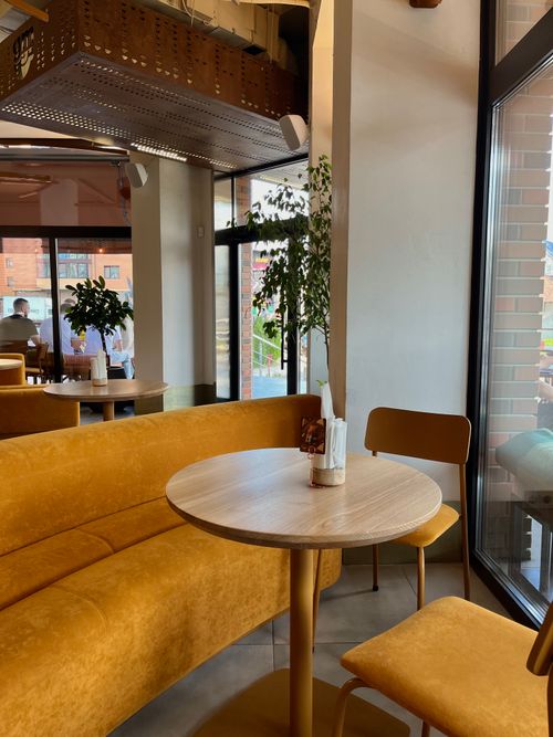Free Chic cafe interior with yellow seating and natural light. Stock Photo