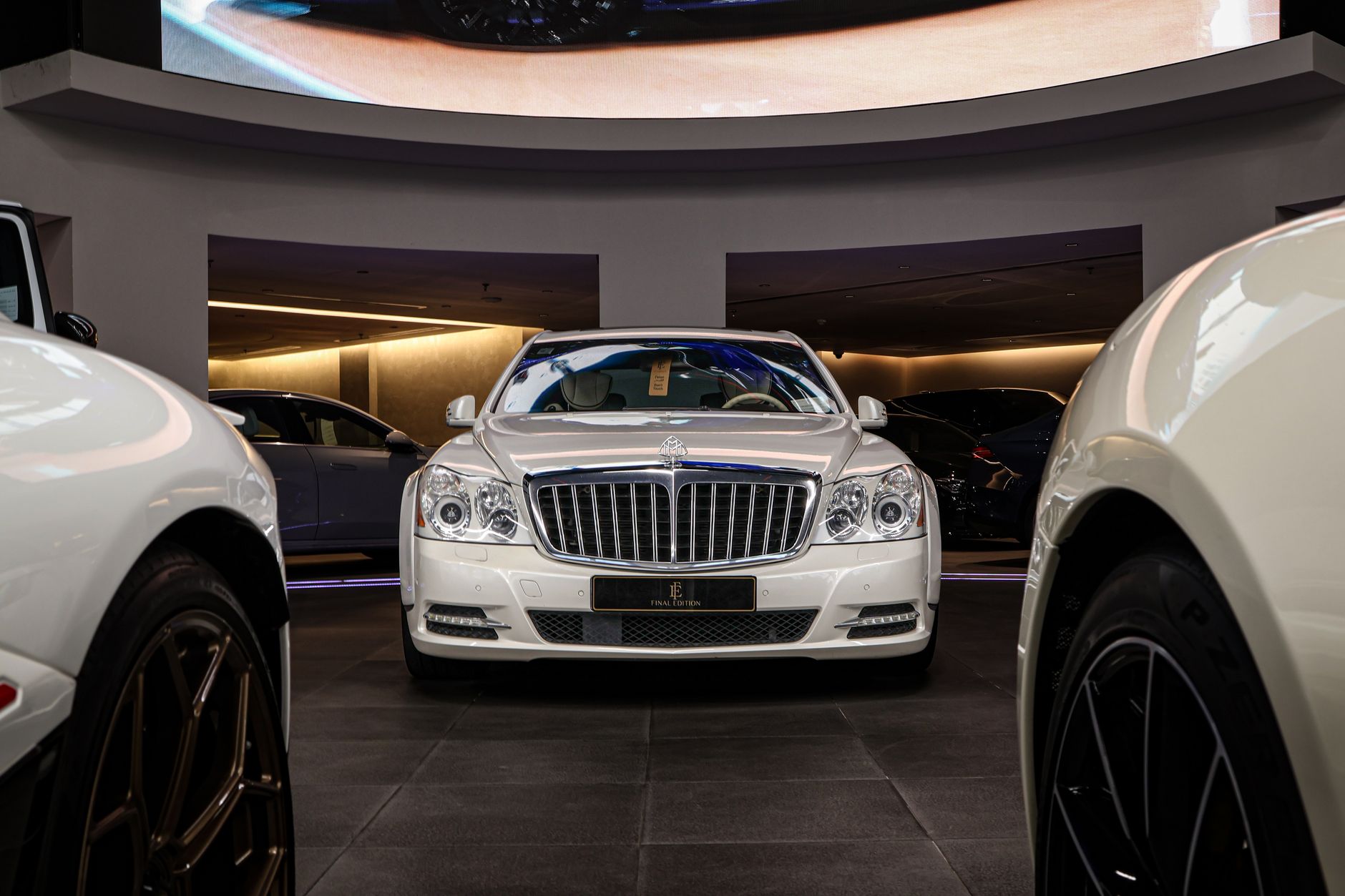 A stunning luxury car display featuring a classic white sedan in a modern showroom setting.