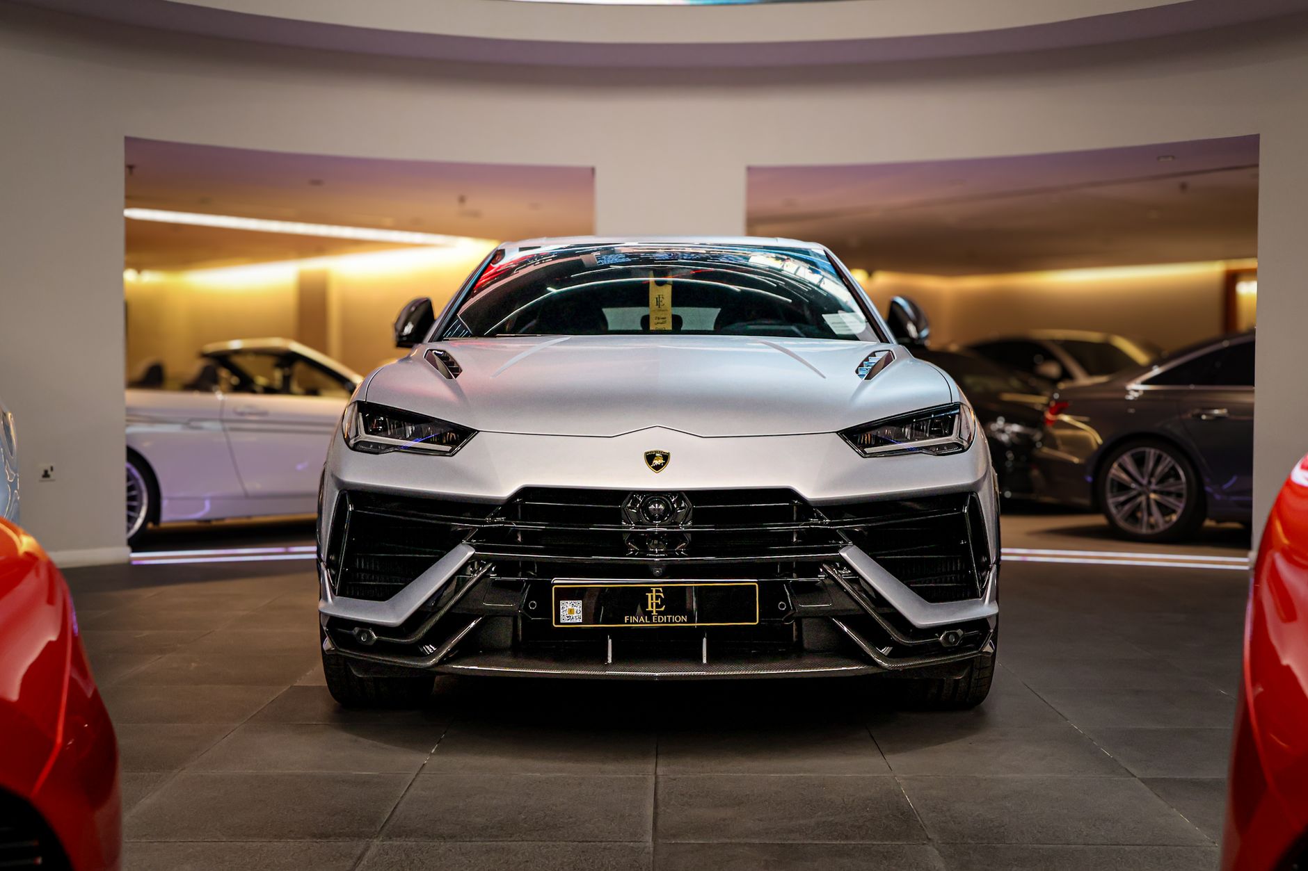 A silver luxury SUV displayed at an indoor showroom under warm lighting, showcasing elegance.
