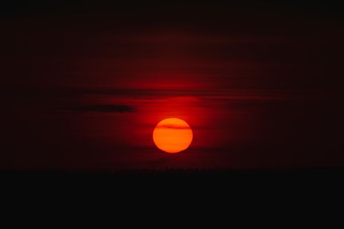 Free Vivid red sunset with glowing sun on the horizon, creating a dramatic natural scene. Stock Photo