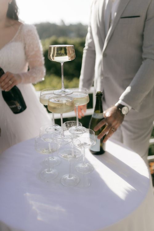 Free Champagne pyramid being filled at an outdoor wedding celebration under bright sunlight. Stock Photo
