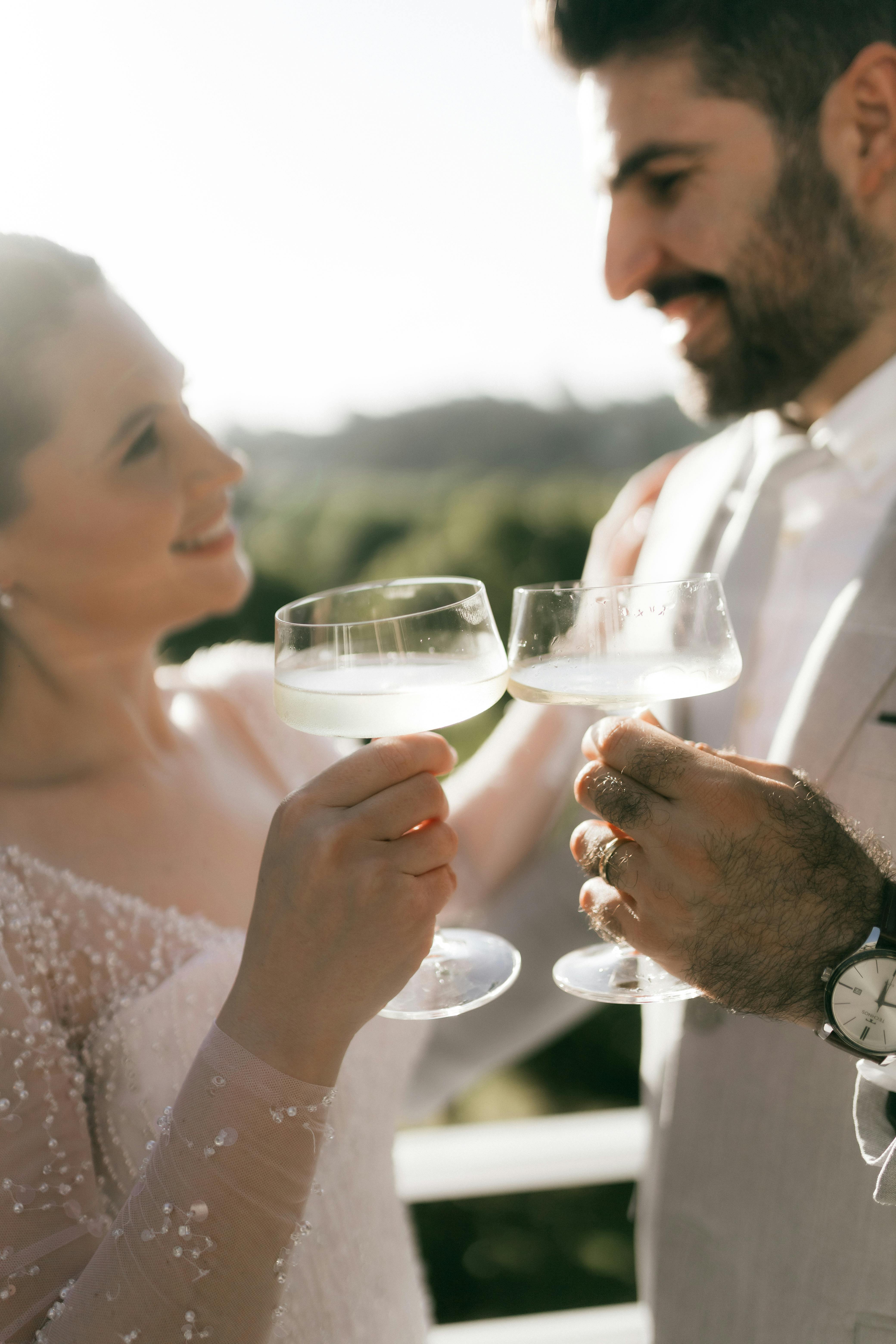 A joyful couple toasting champagne during their outdoor wedding ceremony.