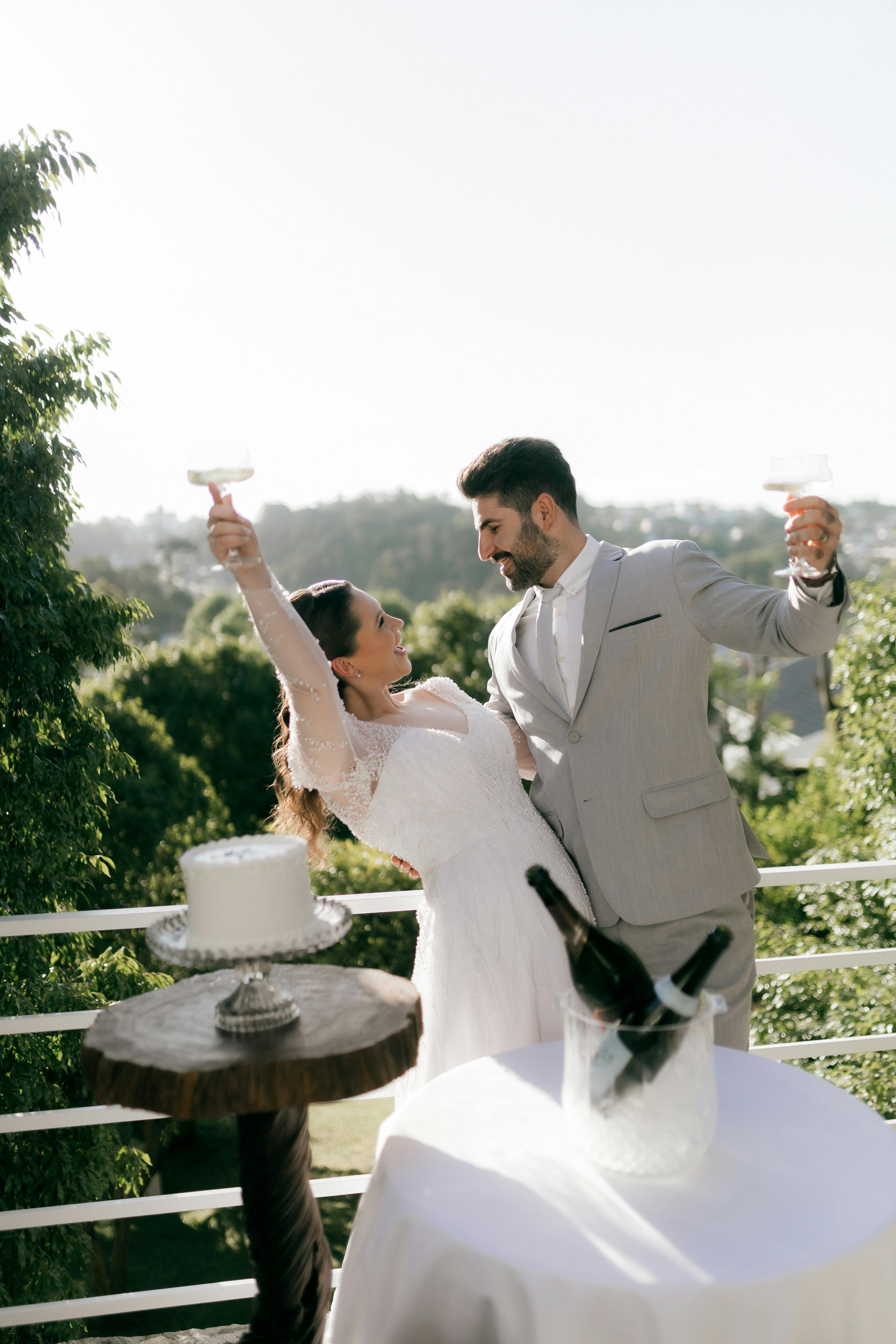 A joyful couple toasting at their outdoor wedding reception with champagne.