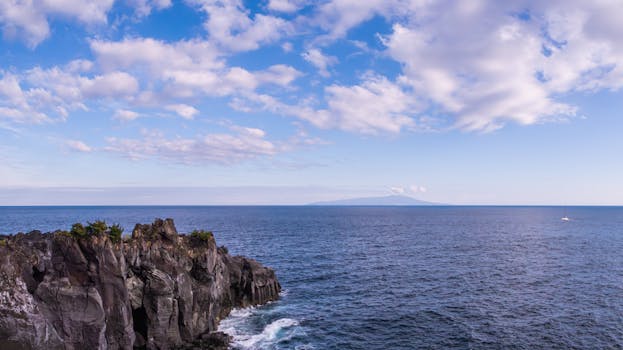 Beautiful coastal landscape featuring rocky cliffs and ocean under a blue sky.