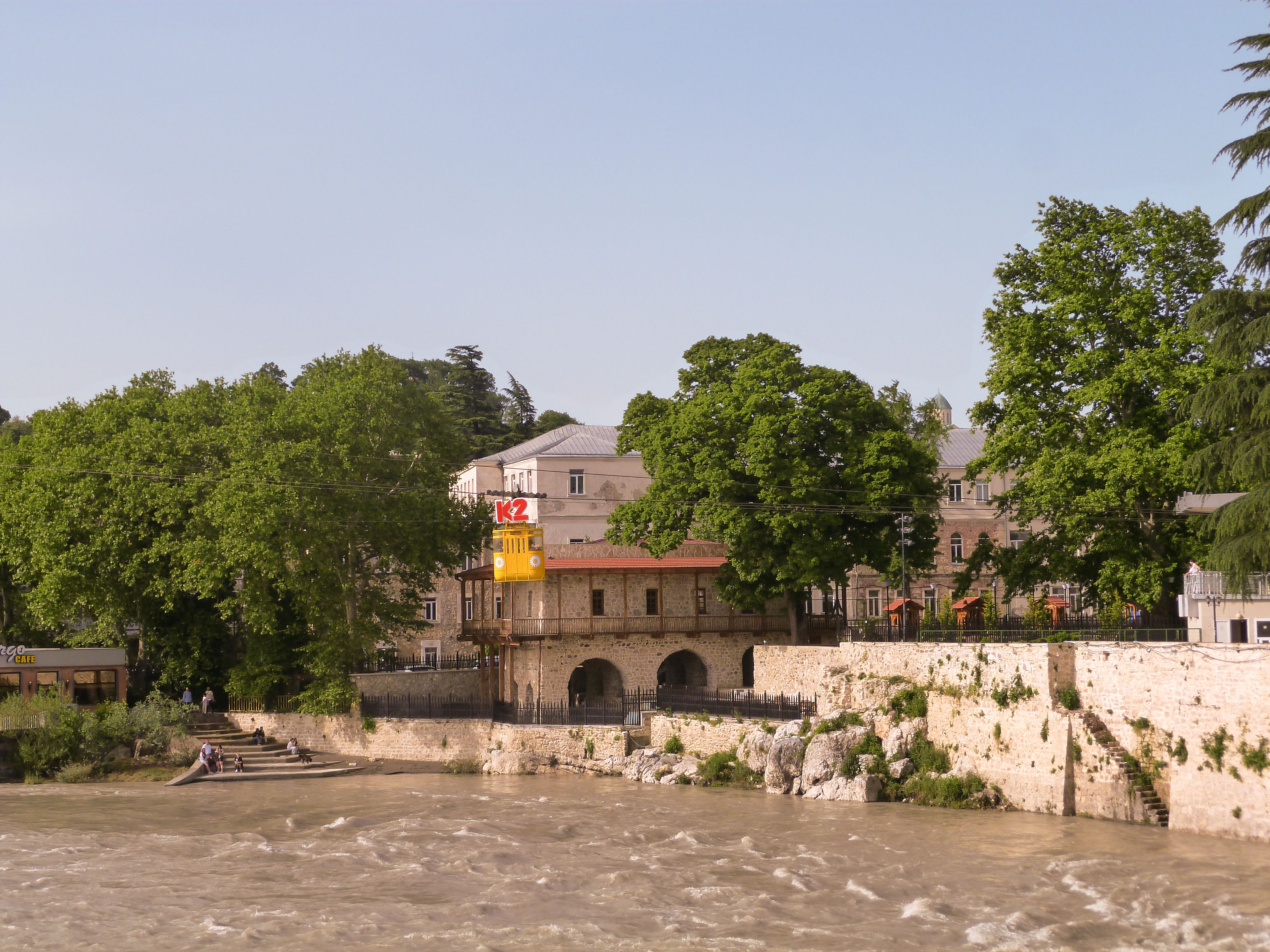 Picturesque riverside architecture surrounded by lush trees in Kutaisi, Georgia.