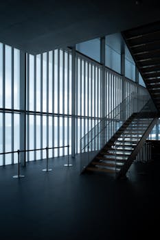 Contemporary interior design featuring glass and steel stairway with natural lighting.