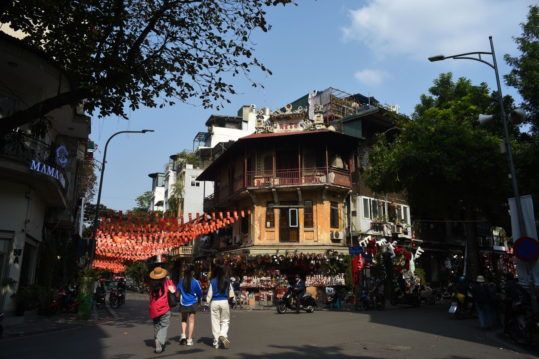 Vibrant scene of people walking through Hanoi's Old Quarter under festive decorations.