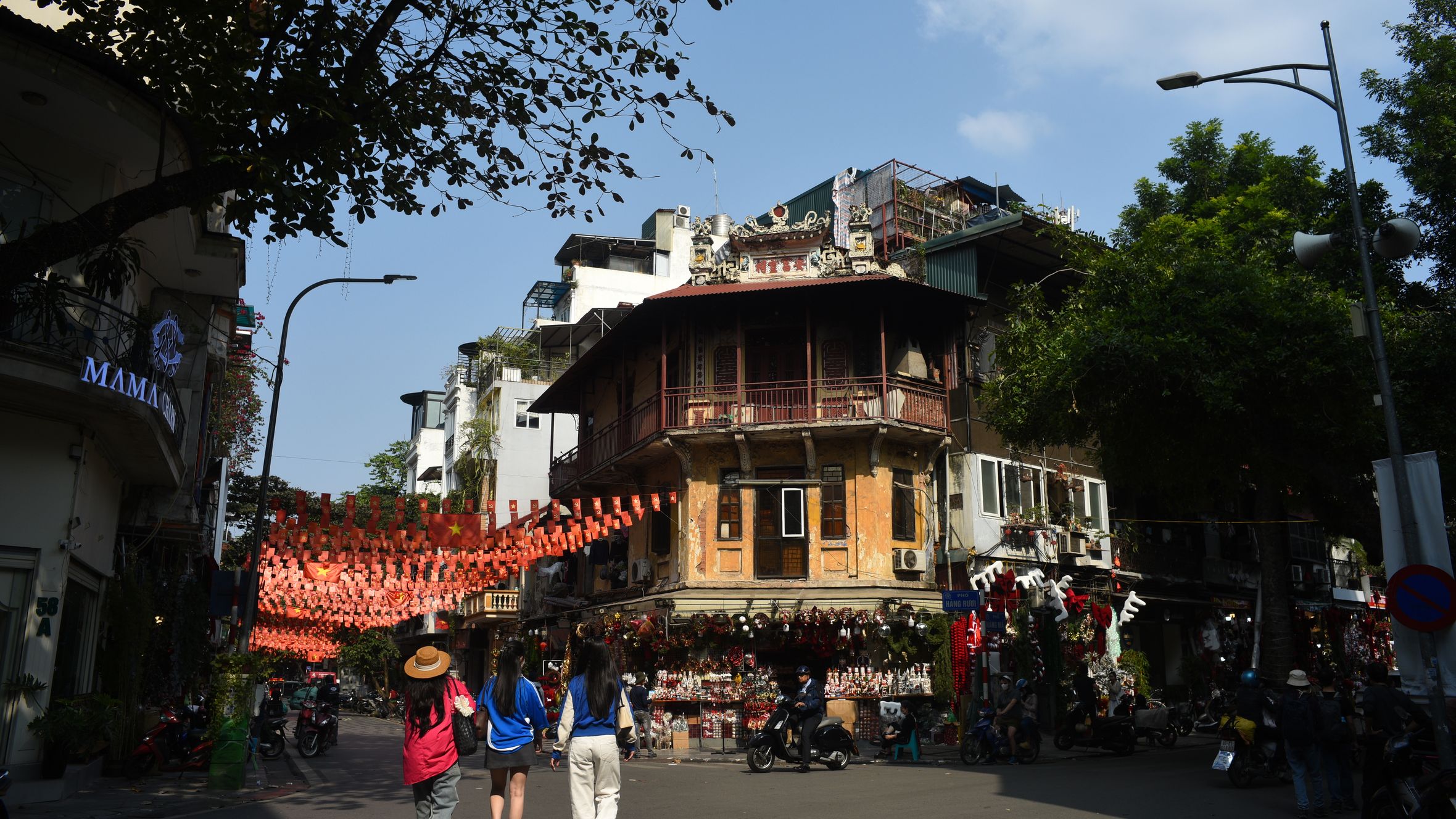 Vibrant scene of people walking through Hanoi's Old Quarter under festive decorations.