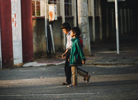Due bambini camminano per strada a Kon Tum, in Vietnam, immortalati nella calda luce del giorno.