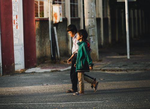 Free Two children walking on a street in Kon Tum, Vietnam, captured in warm daylight. Stock Photo