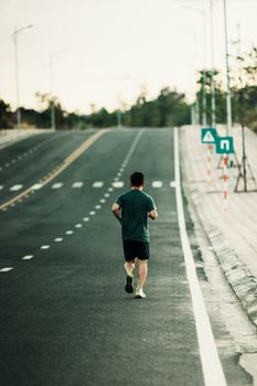 Rear view of a man jogging on an empty road in Kon Tum, Vietnam.