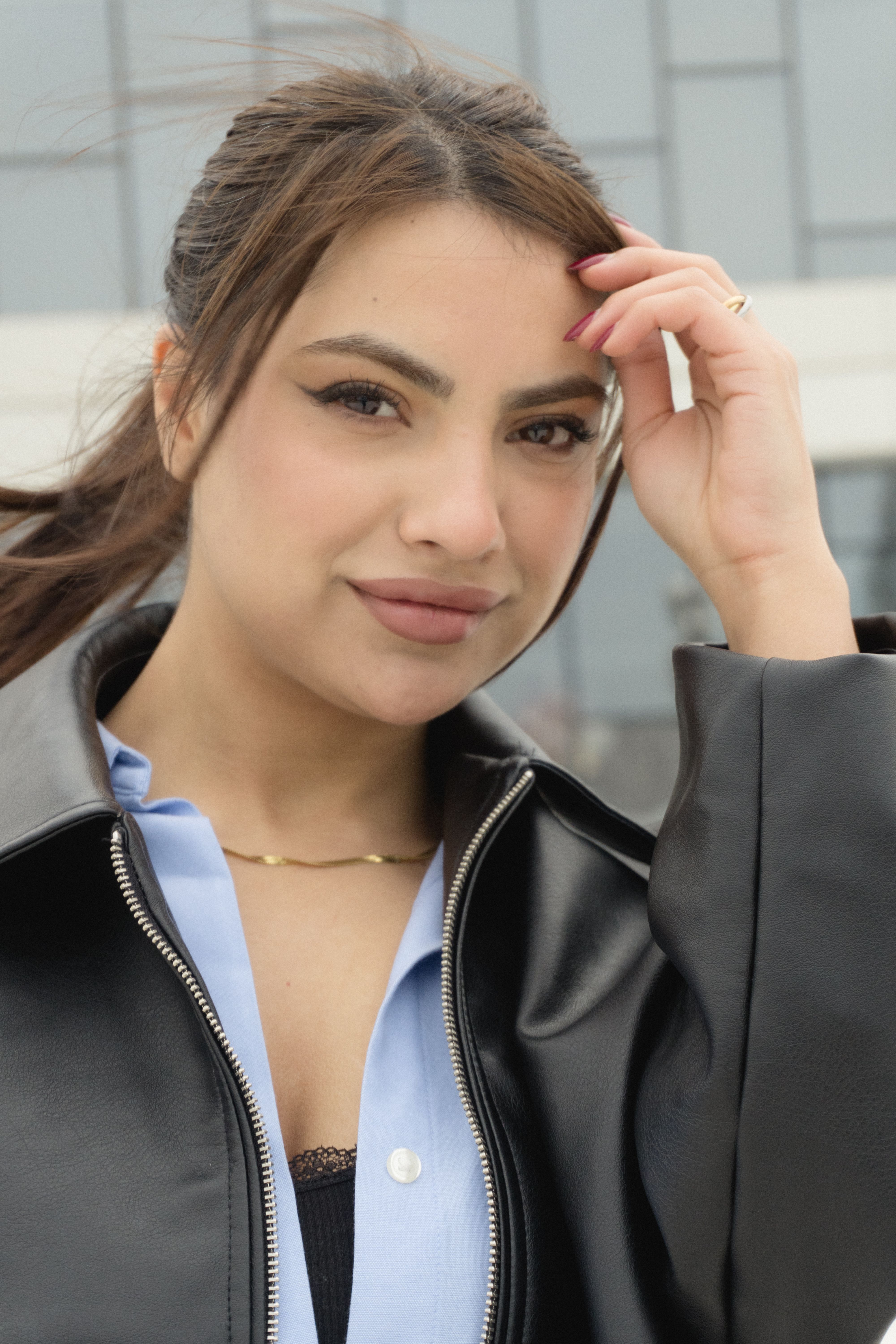 Portrait of a confident woman wearing a black leather jacket standing outdoors, showcasing modern fashion.