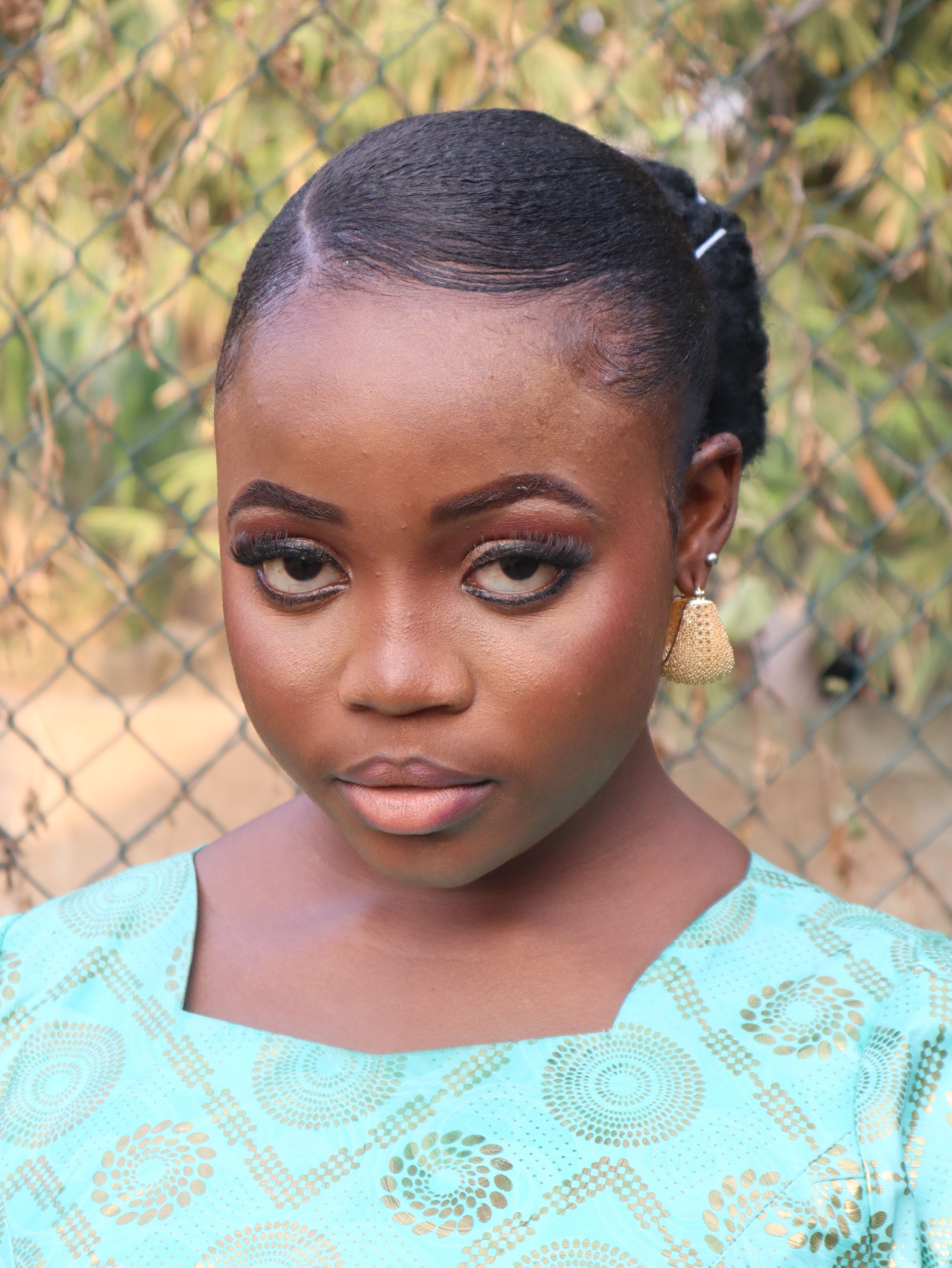 Captivating portrait of a young woman in stylish attire with a natural outdoor background.