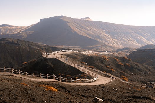A meandering path with wooden railings across a volcanic landscape under a clear sky.