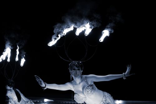 Free Dramatic night fire dance with performers in elegant costumes and fire crowns. Stock Photo