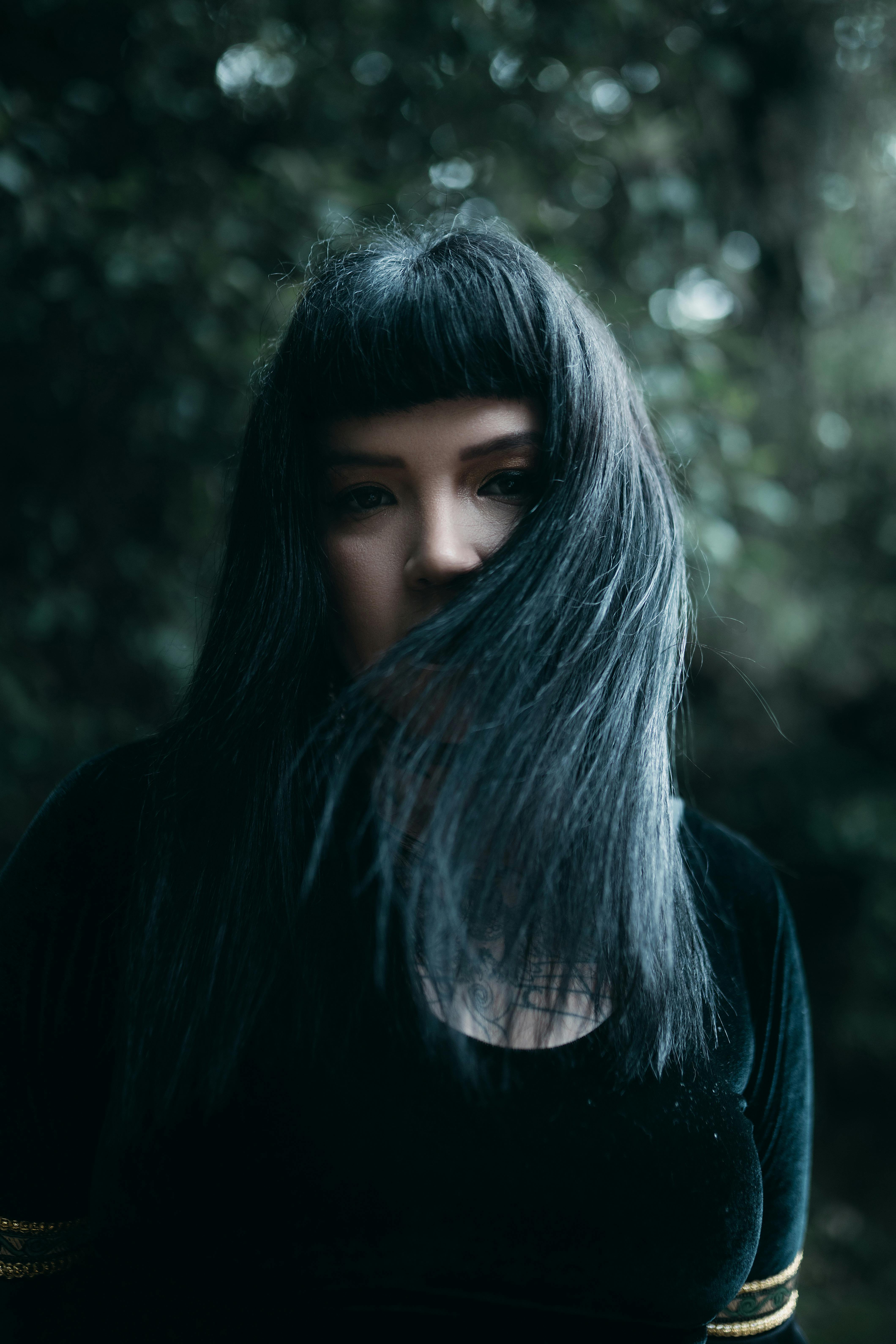 Mysterious portrait of a woman with long dark hair in a natural setting.