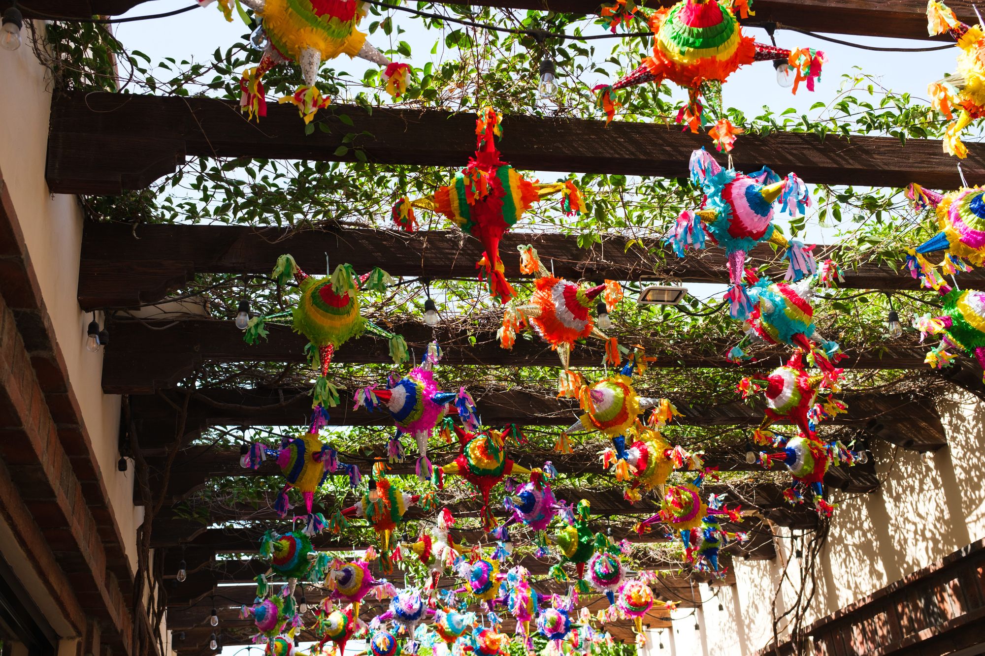 Brightly colored piñatas adorn a pergola in an outdoor celebration space in Cabo, Mexico.