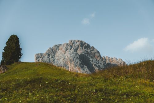 Free A majestic mountain peak under a clear blue sky, surrounded by lush greenery. Stock Photo