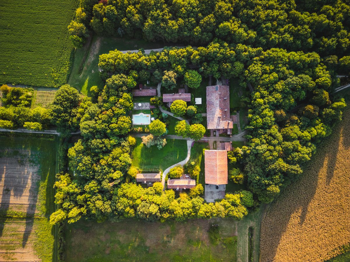 Conac venet înconjurat de copaci, văzut din dronă