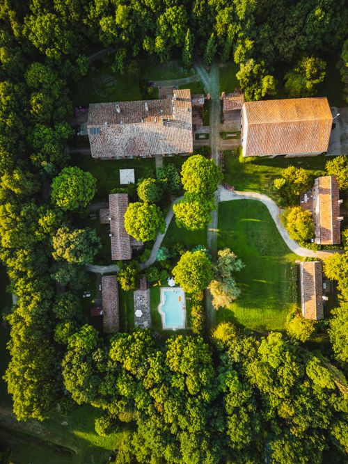 Free Stunning aerial view of a rustic villa surrounded by lush greenery in Italy's countryside. Stock Photo