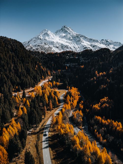 Free A breathtaking aerial photo showcasing Swiss Alps with vivid autumn colors and a winding road. Stock Photo