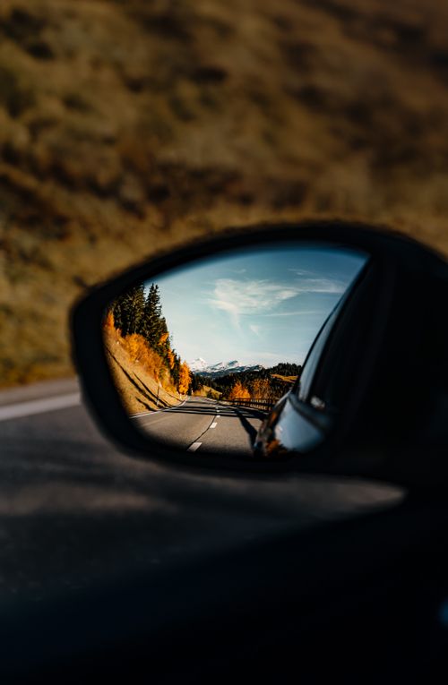 Free Serene autumnal landscape captured in a car's rearview mirror. Stock Photo