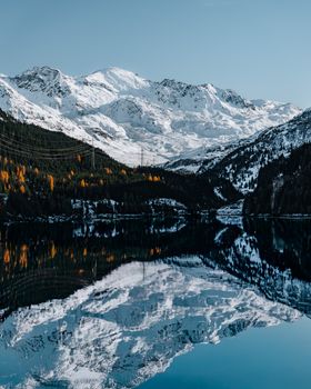Beautiful reflection of snow-capped mountains in a serene alpine lake during winter.