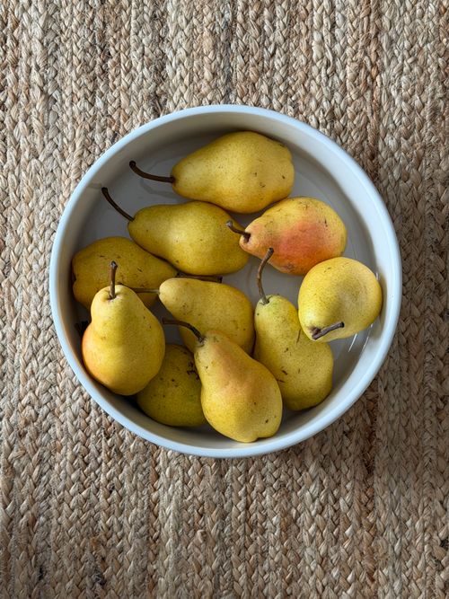 Free A rustic bowl filled with ripe yellow pears on a textured surface, capturing the essence of autumn harvest. Stock Photo