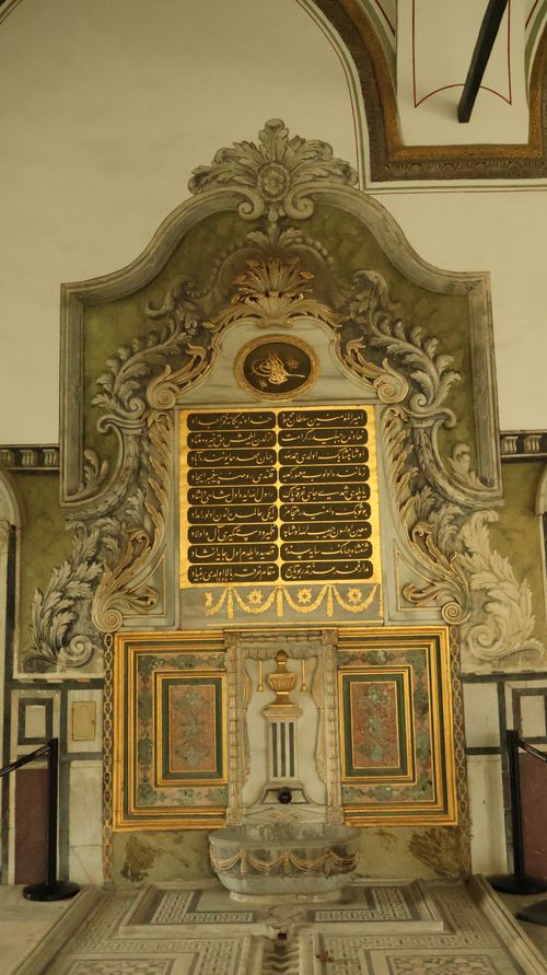 Free Intricate Ottoman-era marble wall fountain with arabesque designs and gold calligraphy. Stock Photo