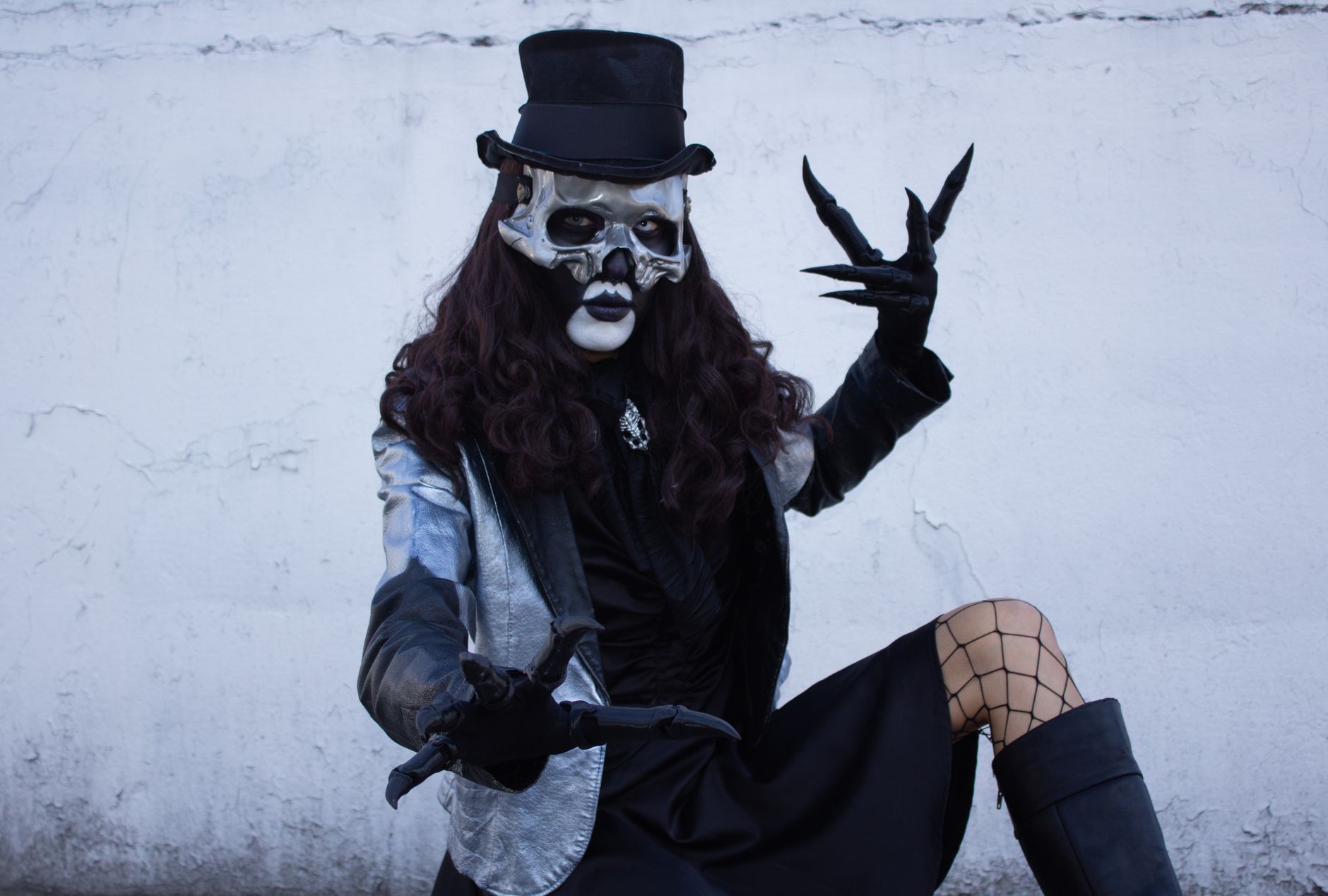 Person in a theatrical skeleton costume and top hat poses dramatically.