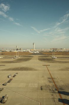 Empty airport runway with control towers under a clear blue sky, ideal for travel industry use.
