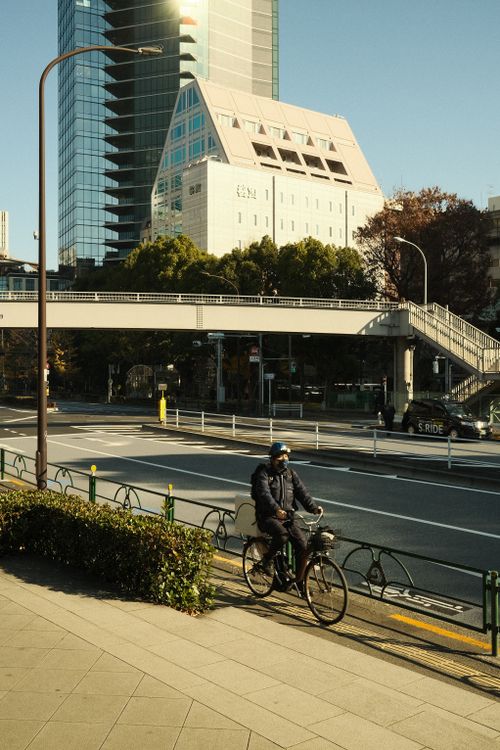 Free A cyclist pedals on a city street beneath modern skyscrapers on a bright day. Stock Photo