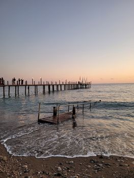 Serene view of a pier at sunset with people enjoying the calm sea in Türkiye. - Fotografer Sidoarjo