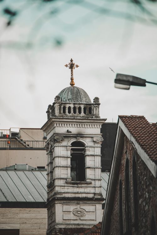 Free An elegant church tower stands tall amidst a modern cityscape, blending heritage with urban life. Stock Photo