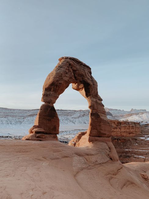 Stunning view of Delicate Arch with snowy backdrop in Arches National Park.